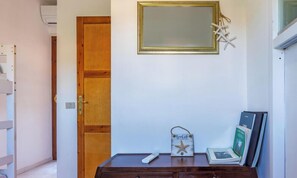 A room with a wooden door, a small table with a remote control, a framed picture, and a decorative item on the wall. - Casa Giacomo - Two Bedroom Apartment, Sleeps 4 (Villasimius)