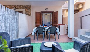 A patio area with a table set for four, surrounded by wicker chairs, and a staircase leading to an upper level.