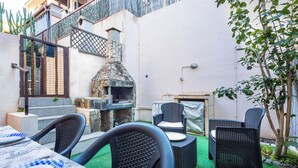 Eine Terrasse im Freien mit Korbmöbeln, einem Steinofen und einer Treppe.