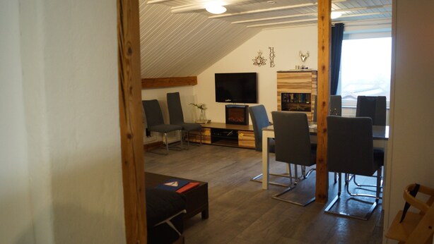 Ein Loft-Wohnzimmer mit Kamin, Fernseher und Essbereich mit Stühlen und Tisch.