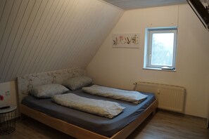 Un dormitorio con techo inclinado, una cama con cabecera, una ventana y un radiador.