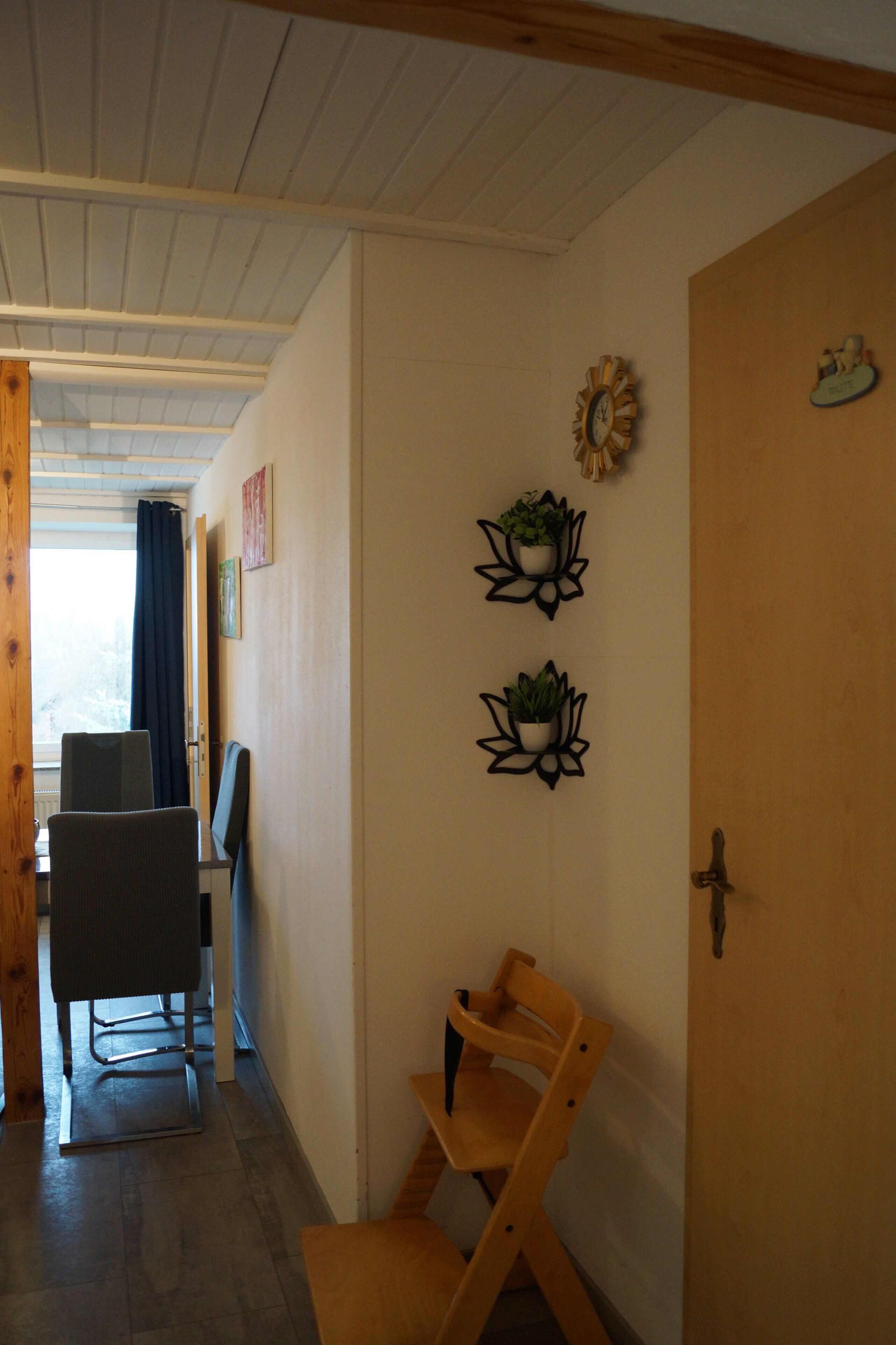 Una stanza con una porta in legno, una scrivania con una sedia e due fioriere a parete.