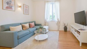 Ein Wohnzimmer mit einer Couch, einem Couchtisch, einem Fernseher und einer Deckenleuchte.