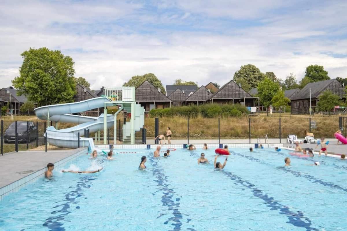 A swimming pool with a water slide, surrounded by houses.