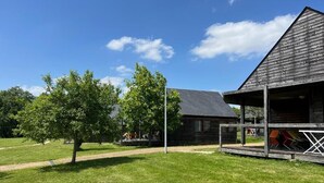 A rustic wooden building with a sloped roof, a covered porch with outdoor seating, and a well-maintained grassy area. - Les Lodges de Sainte-Suzanne (Sainte-Suzanne-and-Chammes)