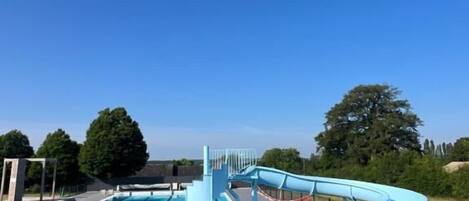 A swimming pool with a water slide and a separate pool area.