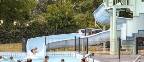 Una piscina con tobogán y una torre de salvavidas.