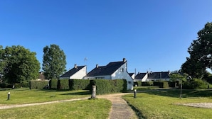 A pathway leading to a row of white houses with dark roofs, surrounded by well-maintained grass and hedges. - Les Lodges de Sainte-Suzanne (Sainte-Suzanne-and-Chammes)