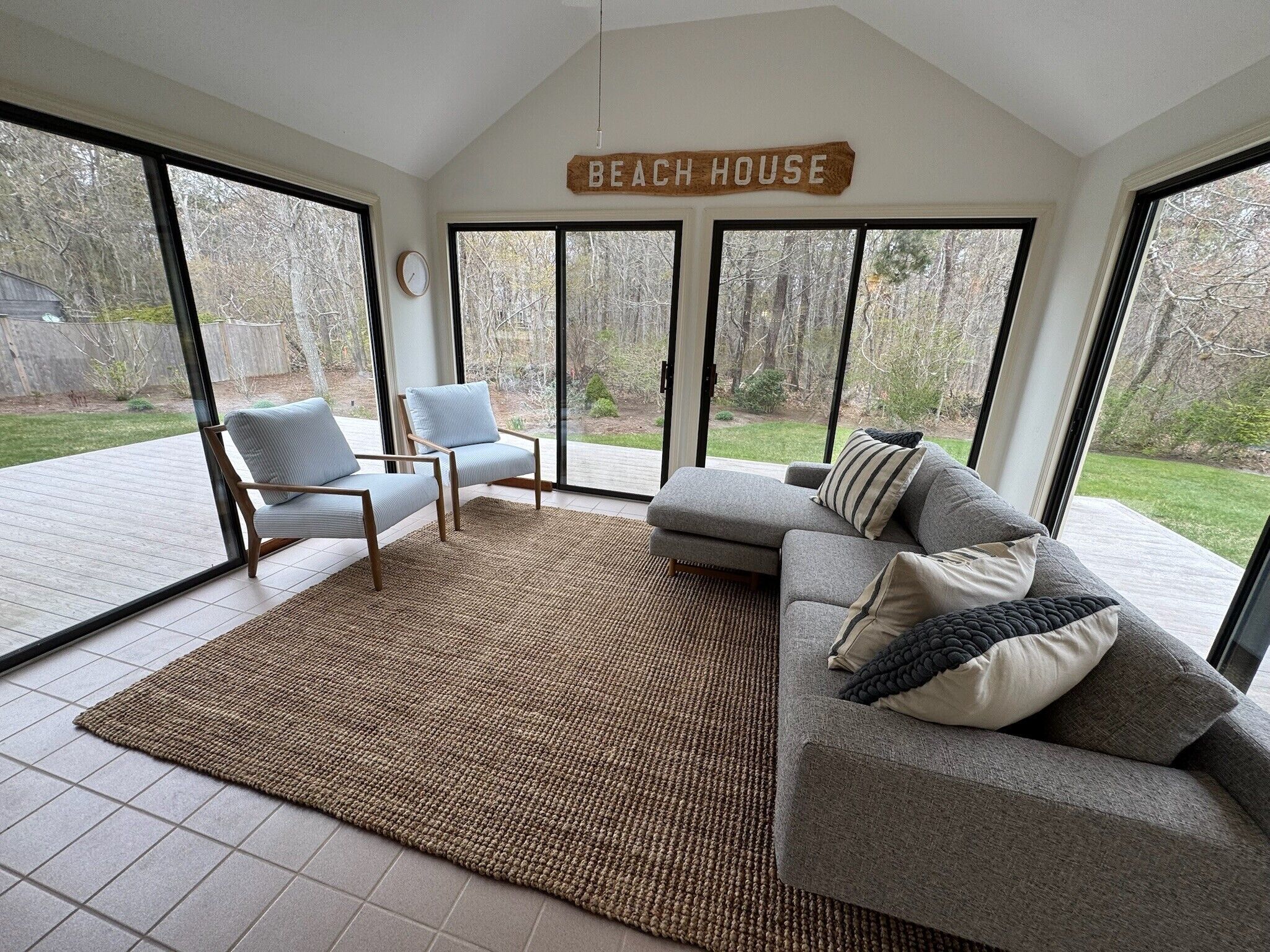 A spacious living area with a large sliding glass door, a sofa, two armchairs, and a rug.