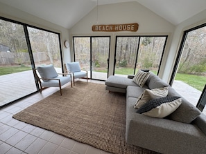 A spacious living area with a large sliding glass door, a sofa, two armchairs, and a rug.