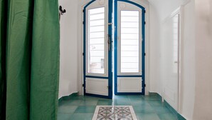 Une pièce avec un rideau vert, un sol carrelé et une paire de portes à cadre bleu.