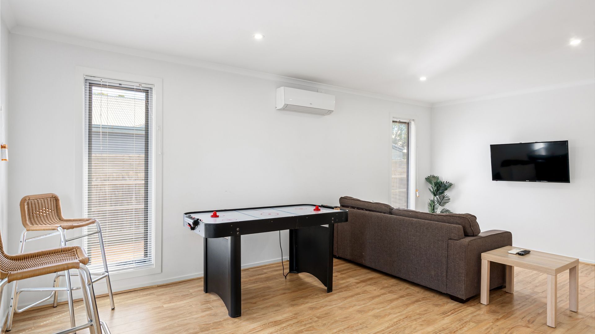 Een moderne woonkamer met een pooltafel, een bank, een televisie en een bijzettafeltje.