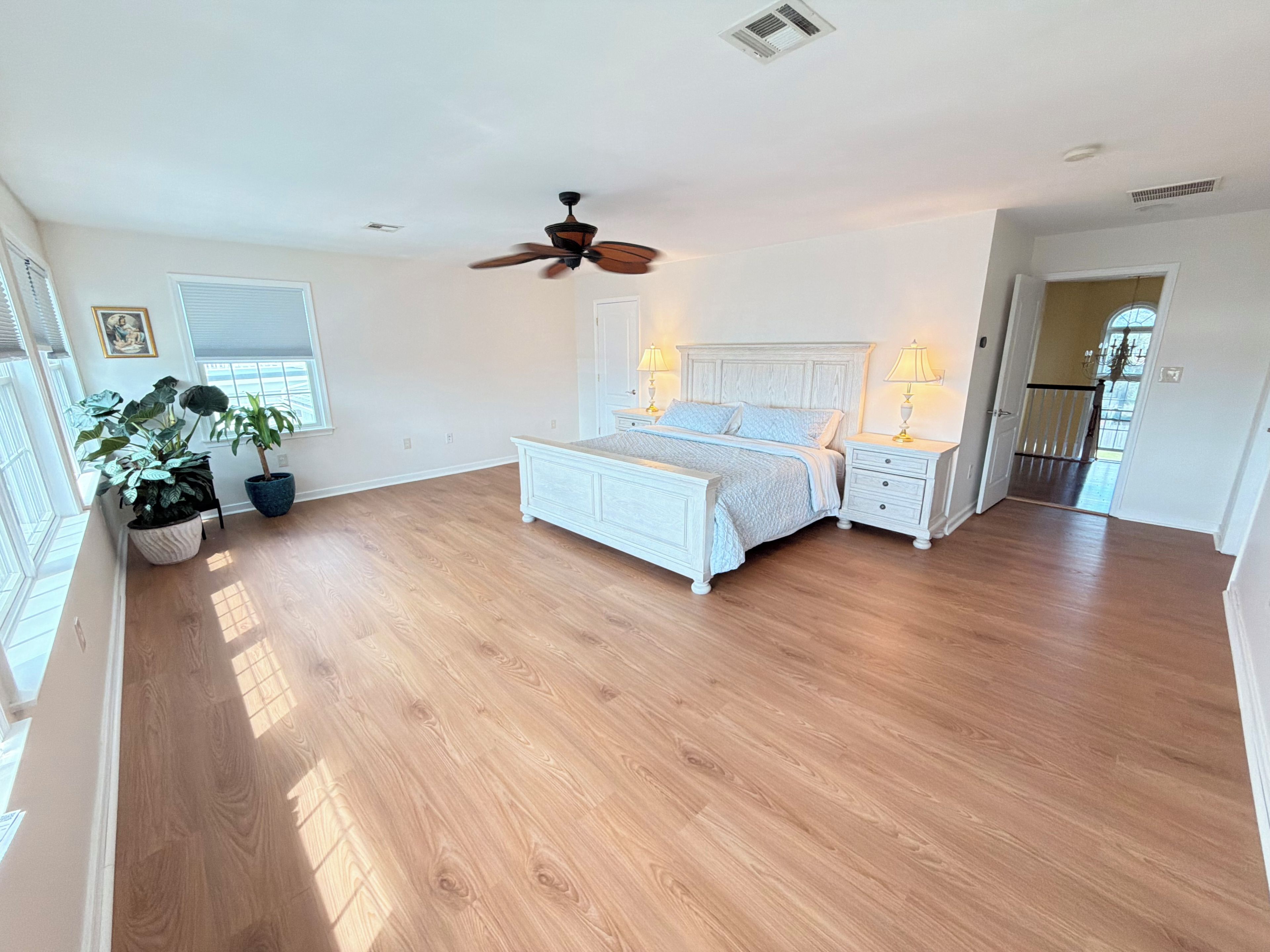 A spacious bedroom with a large bed, bedside tables, and a ceiling fan.