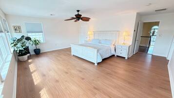 A spacious bedroom with a large bed, bedside tables, and a ceiling fan.