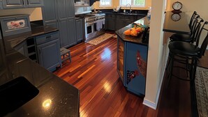 A kitchen with dark cabinets, a wooden floor, a refrigerator, a stove, and a sink. - Lagoon Luxe at Osborn Island - Private Dock - Minutes to LBI and Graveling Beach (Little Egg Harbor Township)