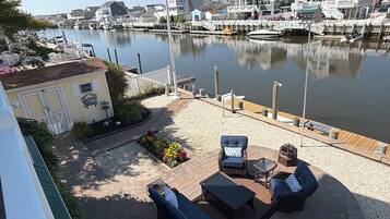 A waterfront patio with outdoor furniture, a flag, and a marina in the background.