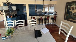 A dining area with a table, chairs, a laptop, and a vase with flowers. - Lagoon Luxe at Osborn Island - Private Dock - Minutes to LBI and Graveling Beach (Little Egg Harbor Township)