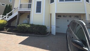 A multi-story residential building with a garage, a covered front porch, and a staircase leading to an upper level. - Lagoon Luxe at Osborn Island - Private Dock - Minutes to LBI and Graveling Beach (Little Egg Harbor Township)