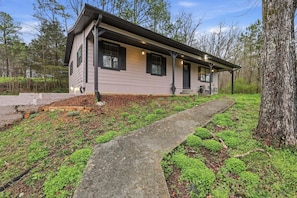 A single-story house with a covered porch, a stone pathway, and a well-maintained garden.