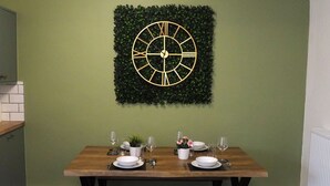 A dining table set with plates, glasses, and a decorative wall clock. - 4 Bed • Parking • Close to M4 – Ideal for Work (Neath Port Talbot Principle Area)