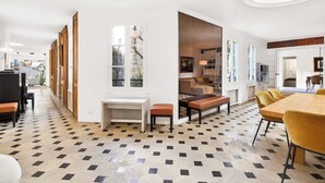 Un interno moderno con pavimento a scacchi, un'area pranzo con sedie gialle e un'ampia finestra.