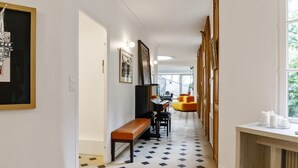 Un corridoio con pavimento decorato, una panca, un tavolo con tazze e opere d'arte incorniciate alle pareti.