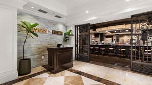 A hotel lobby with a reception desk, a bar area, and a sign that reads 'SAVERN TOWN'.
