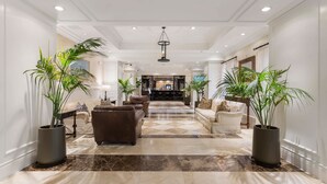 A spacious lobby with a marble floor, leather sofas, and large potted plants.