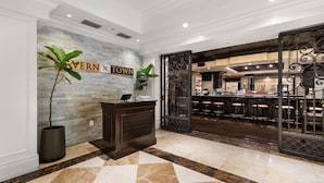 A hotel lobby with a reception desk, a bar area, and a sign that reads 'SAVERN TOWN'. - Pool View Suite | Beachside Resort (Key West)