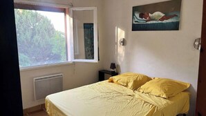 Un dormitorio con cama, ventana, cuadro y radiador.