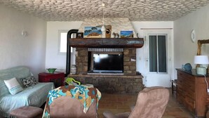Una sala de estar con techo de piedra, chimenea, ventilador de techo y sofá.
