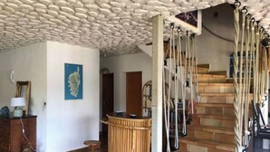 Una habitación con techo de piedra, barra de madera, escalera y un mapa en la pared.