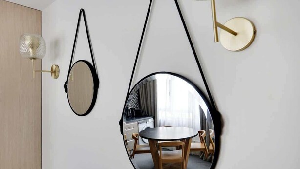A room with a round mirror, a wall-mounted light fixture, and a round table with chairs. - Bel appartement pour 4 - Palais des Expositions (Paris)