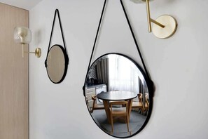 Ein Zimmer mit einem runden Spiegel, einer Wandleuchte und einem runden Tisch mit Stühlen.