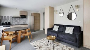 A modern living room with a sofa, coffee table, and dining area. - Bel appartement pour 4 - Palais des Expositions (Paris)