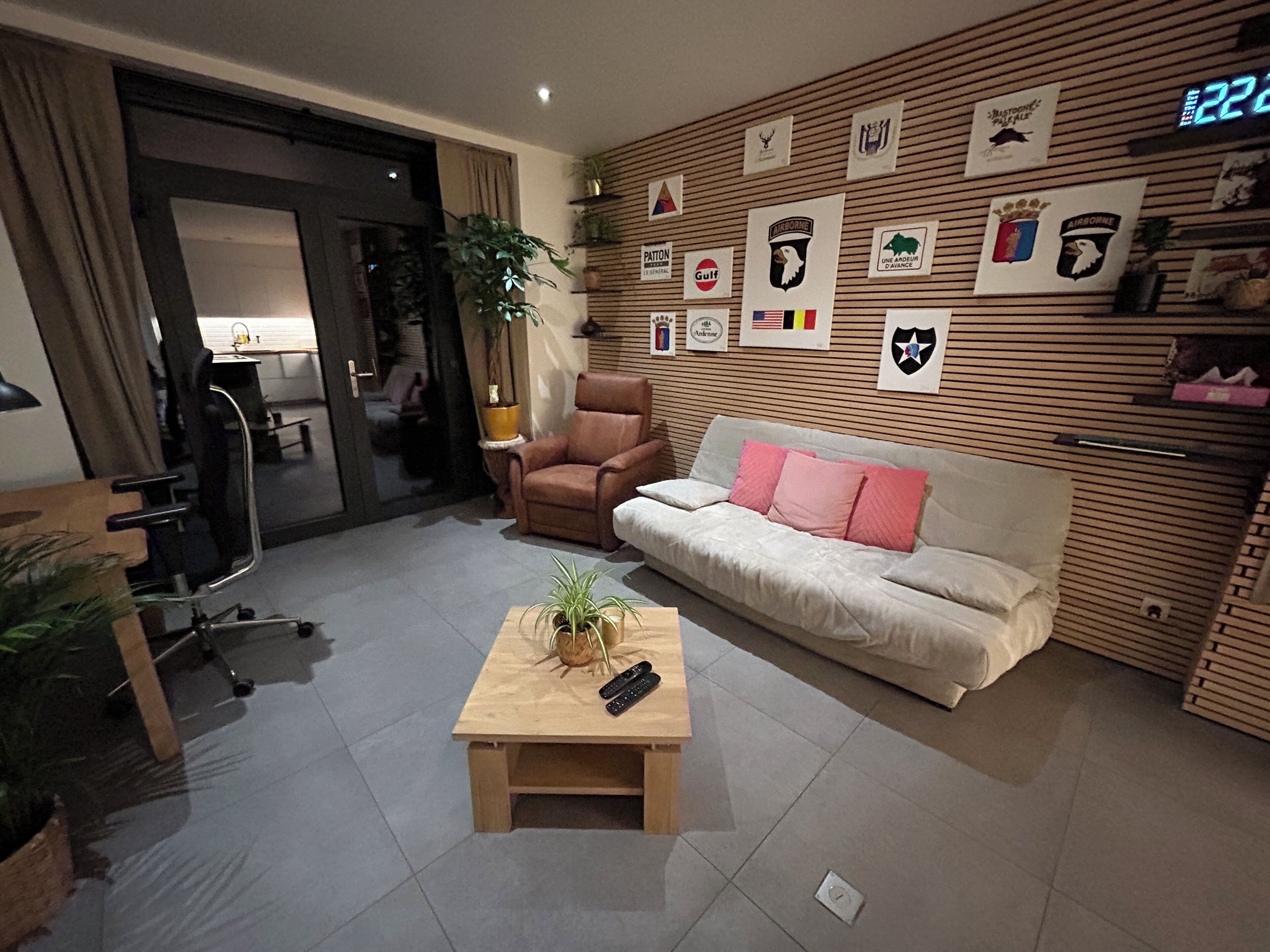 A living room with a sofa, a coffee table, a chair, and a wall decorated with various emblems.