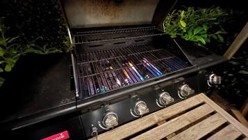 A barbecue grill with a 'barbecook' label, four control knobs, and a grate with visible food residue.