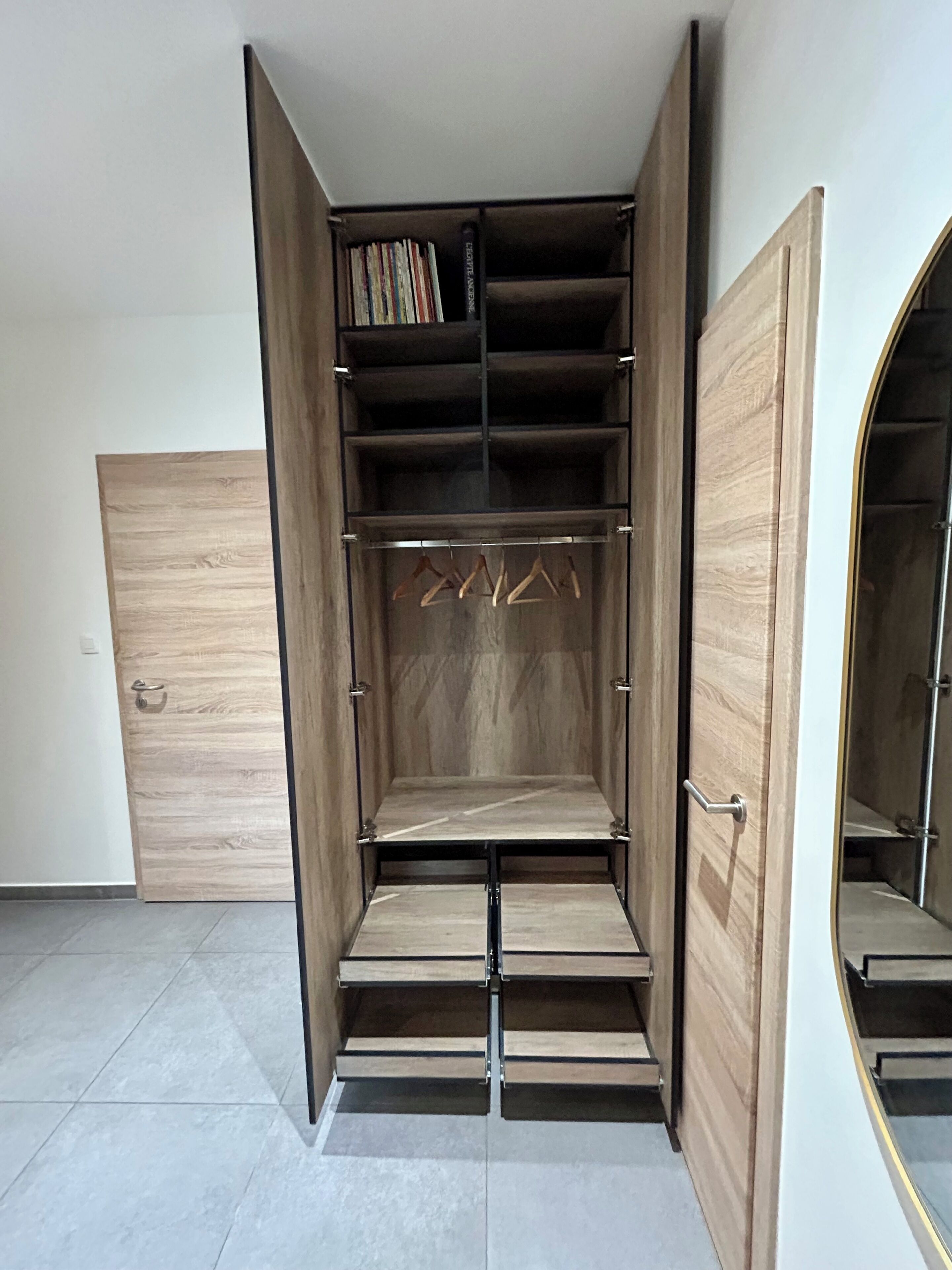 A walk-in closet with open doors, featuring multiple shelves and hanging space.