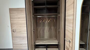 A walk-in closet with open doors, featuring multiple shelves and hanging space.
