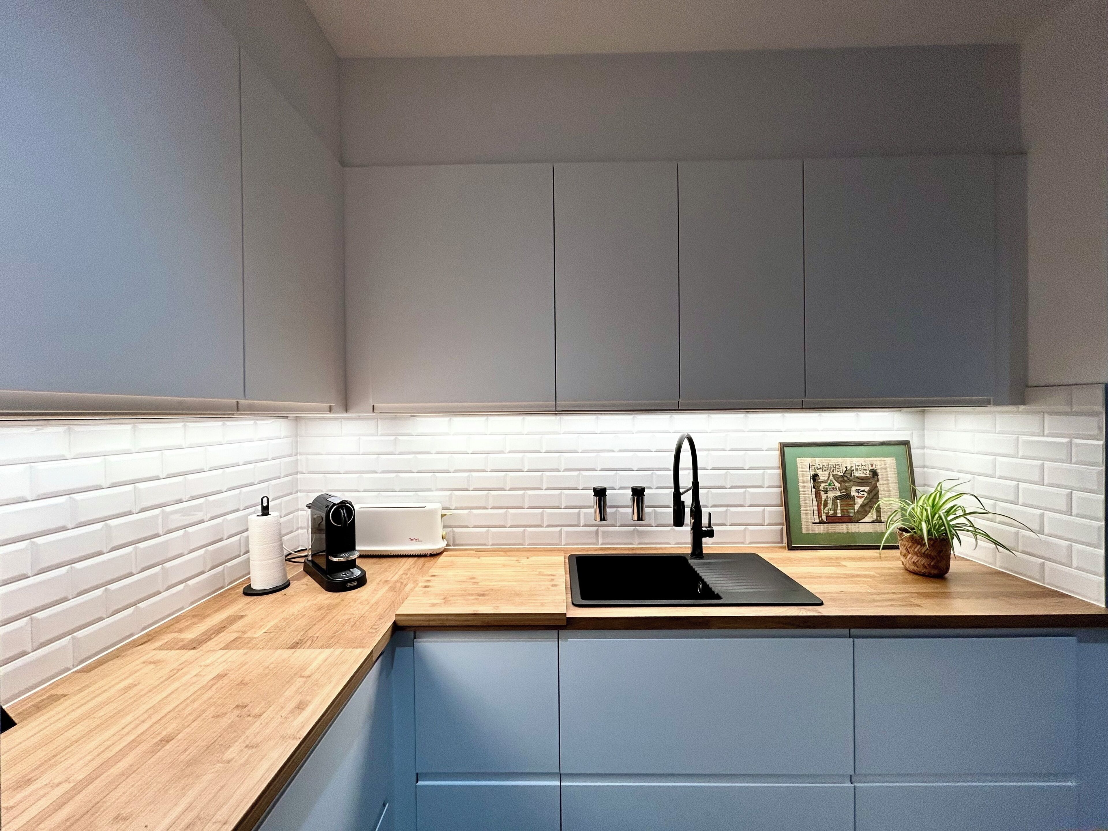 Een moderne keuken met een houten aanrecht, een zwarte spoelbak en een koffiezetapparaat.