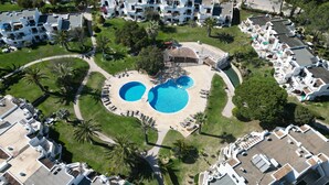 Ett flygbildsbild av ett semesterområde med två pooler, palmer och vita byggnader.