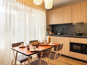 A modern kitchen with wooden cabinets, a dining table with chairs, and a window with sheer curtains. - Rare loft with a stylish patio - Eiffel Tower (Paris)