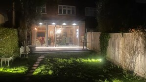 Una casa amb un porxo ben il·luminat, una porta visible i una petita zona de jardí.