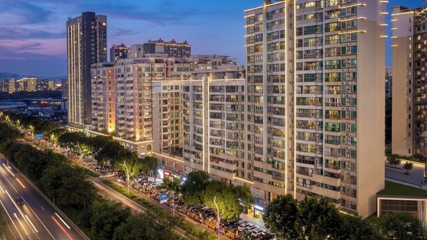 A high-rise residential building with multiple balconies, a well-lit street, and a clear view of the surrounding urban area. - Lofi Hotel - Pazhou Canton Fair Center (Guangzhou)