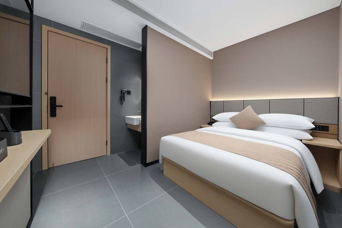 Una habitación de hotel moderna con cama, mesita de noche y escritorio con silla.