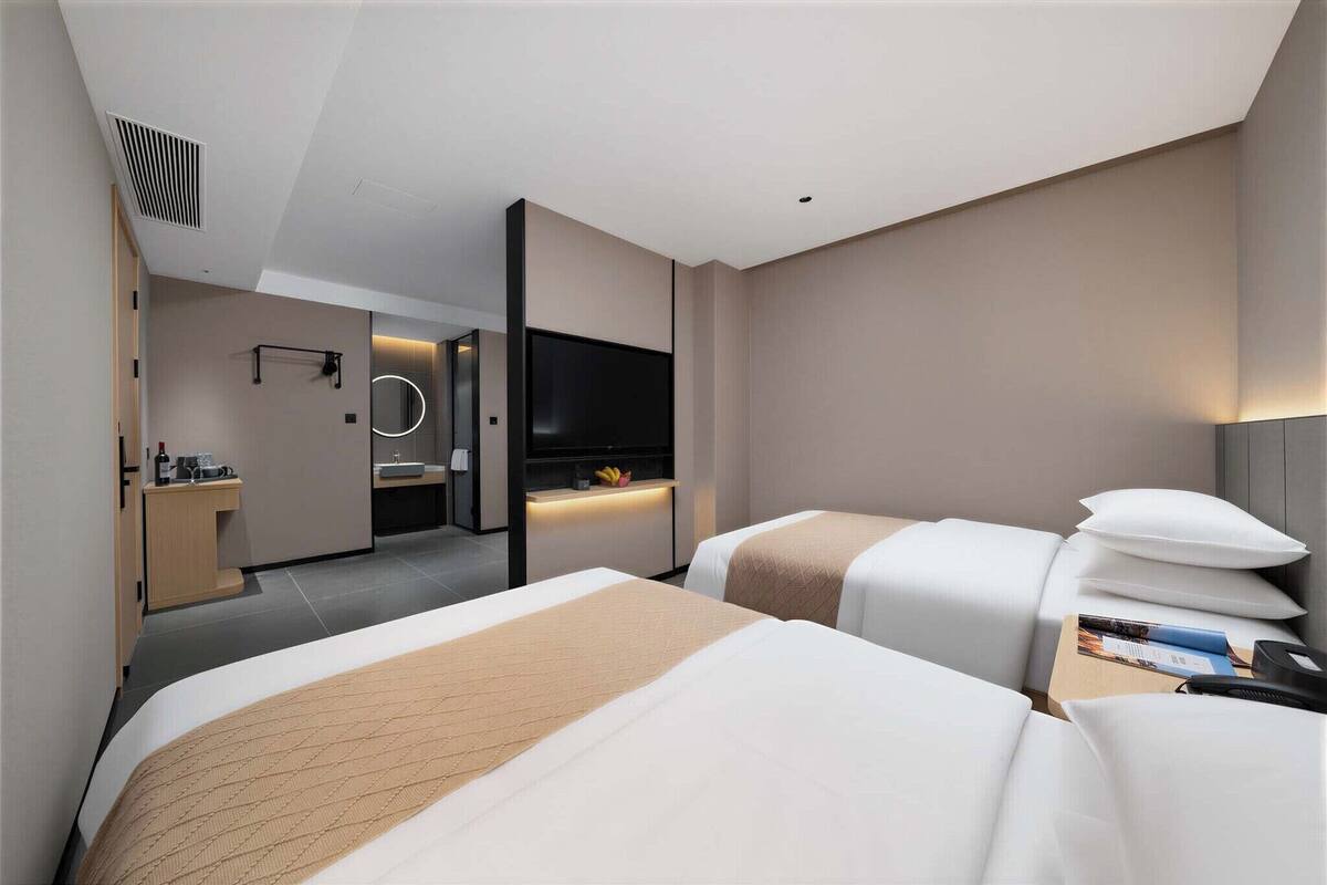 Una habitación de hotel moderna con dos camas, televisión, escritorio y baño.