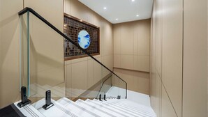 A modern staircase with glass railings and a decorative wall panel. - Lofi Hotel - Pazhou Canton Fair Center (Guangzhou)