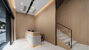 A reception area with a modern counter, a staircase, and a view of the outside. - Lofi Hotel - Pazhou Canton Fair Center (Guangzhou)