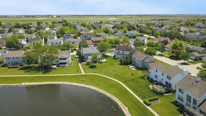 A residential area with houses, a pond, and a clear sky.
