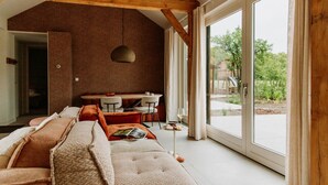 Een ruime woonkamer met een groot raam, een eettafel en een gezellige zithoek.